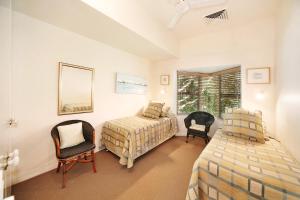 1 Schlafzimmer mit 2 Betten, 2 Stühlen und einem Spiegel in der Unterkunft Alderly Apartment 10, Little Cove in Noosa Heads