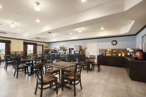 a restaurant with tables and chairs and a kitchen at Days Inn & Suites by Wyndham Galveston West/Seawall in Galveston