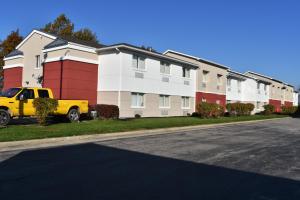 een gele vrachtwagen geparkeerd voor een rij huizen bij Motel 6-Anderson, IN - Indianapolis in Anderson