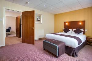バーミンガムにあるApollo Hotelの大きなベッドと椅子が備わる広いホテルルームです。