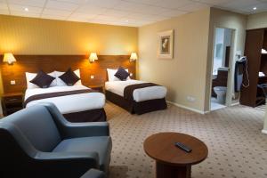 a hotel room with two beds and a chair at Apollo Hotel in Birmingham