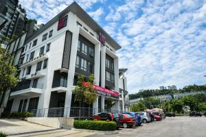 un edificio blanco con coches estacionados en un estacionamiento en RHR Hotel - Selayang en Batu Caves