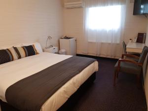 a bedroom with a bed and a desk and a window at Morphett Arms Hotel in Adelaide