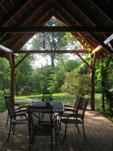 eine Terrasse mit einem Tisch und Stühlen unter einem Pavillon in der Unterkunft Cserépmadár szállás és Csinyálóház in Velemér