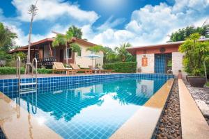 a villa with a swimming pool in front of a house at Siray Green Resort in Phuket