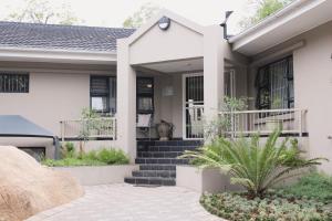 a white house with a porch and stairs at Vineyard On The Hill in Nelspruit