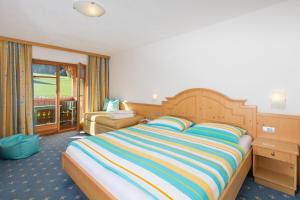 ein Schlafzimmer mit einem großen Bett mit einer bunten gestreiften Decke in der Unterkunft Hotel Lindnerhof in St. Lorenzen
