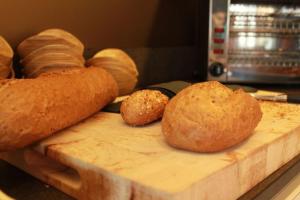 ein Laib Brot und Brötchen auf einem Schneidebrett in der Unterkunft Hotel Astel in De Haan