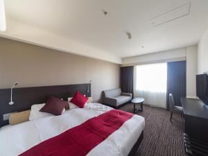 una camera d'albergo con un grande letto e una sedia di KKR Hotel Nagoya a Nagoya