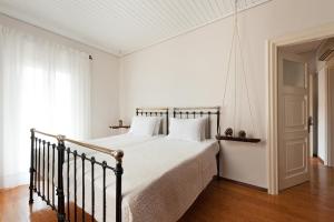 um quarto com uma cama grande com lençóis brancos e uma janela em Corfu Town Stylish Apartment em Corfu Town