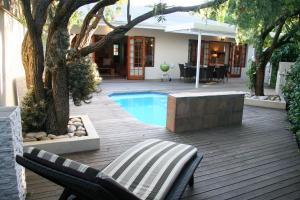 a patio with a pool and chairs and a house at Cape Robin Cottage in Franschhoek