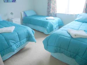 a bedroom with two beds with blue comforters at SilverSands in Waihi Beach
