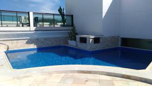 a large blue swimming pool in a building at Loft da Prainha in Arraial do Cabo