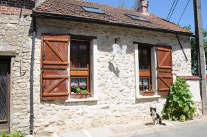 a dog sitting in front of a stone building with windows at Gîte Mi Do in Tourly