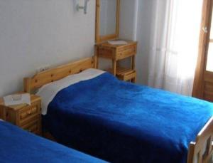 a bedroom with a blue bed and a mirror at Hotel Alexandros in Ormos Panagias