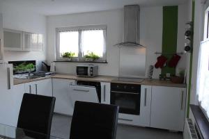 エメンディンゲンにあるAppartement am Elzdammのキッチン(白い家電製品、黒い椅子付)