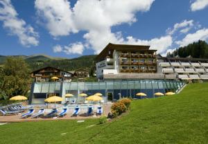 a building with chairs and umbrellas in front of it at Family Resort Rainer in Sesto