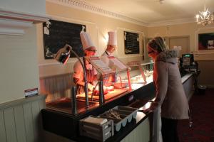 a woman standing in front of a counter with three chefs at The Parkway Hotel in Dunmanway