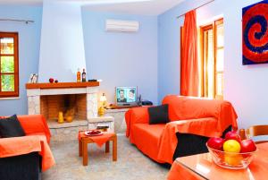 Elle comprend un salon doté d'un mobilier orange et d'une cheminée. dans l'établissement Lefkada Villas by Omikron Selections, à Vavkerí