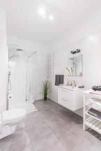 uma casa de banho branca com um chuveiro e um WC. em Palm Aparts Warsaw em Varósvia