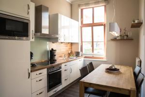 eine Küche mit einem Holztisch und eine Küche mit weißen Schränken in der Unterkunft Autorenhaus Franz Kafka in Ahlbeck
