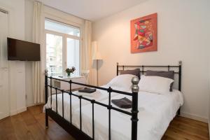 - une chambre avec un lit, une télévision et une fenêtre dans l'établissement Old / New Pijp, à Amsterdam