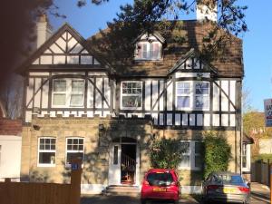 a house with two cars parked in front of it at Gatwick Castle B&B in Horley