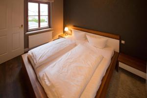 um quarto com uma cama com lençóis brancos e uma janela em Autorenhaus Rainer Maria Rilke em Ahlbeck