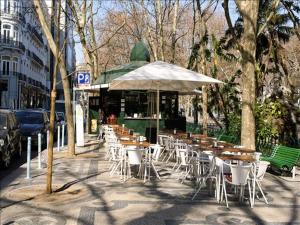 Un grupo de mesas y sillas con una sombrilla. en Garcia Place, en Lisboa