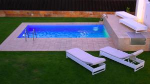uma piscina com duas espreguiçadeiras ao lado em Villa Calma Luxury Villa em Maspalomas