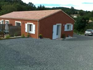 la Villa rouge Ardèche "le Baya" في Ucel: مبنى من الطوب الأحمر مع أبواب بيضاء وممر حصى