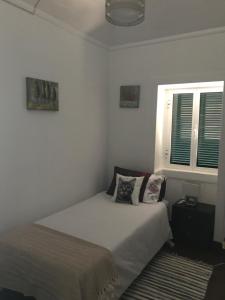 a white bedroom with a bed and two windows at Casa da Maria in Prazeres