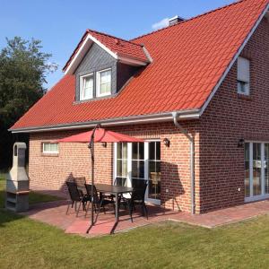 una casa de techo rojo con mesa y sillas en Ferienhaus Seestern, en Garrel