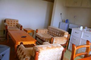 a living room with chairs and a table and a kitchen at Sheywe Hotel Kakamega in Kakamega