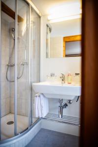 ein Bad mit einem Waschbecken und einer Dusche in der Unterkunft Hotel Nufenen in Ulrichen