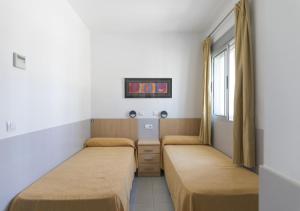 a hotel room with two beds and a television at Albergue Inturjoven Malaga in Málaga