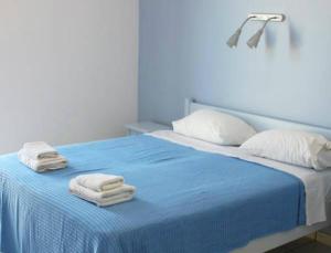 ein Schlafzimmer mit einem blauen Bett und Handtüchern darauf in der Unterkunft Alvi Studios in Perdika