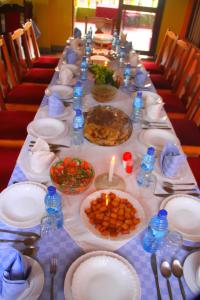 einen langen Tisch mit Teller mit Essen und einer Kerze in der Unterkunft Sheywe Hotel Kakamega in Kakamega