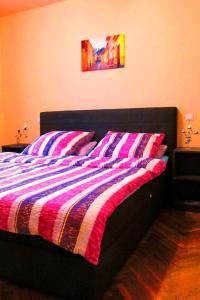 a bed with a striped comforter in a bedroom at Citadel Park Apartment in Sighişoara
