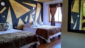 a bedroom with two beds and a wall with a painting at Residencial del Maule in Linares