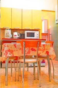a kitchen with a table and chairs with yellow cabinets at Citadel Park Apartment in Sighişoara