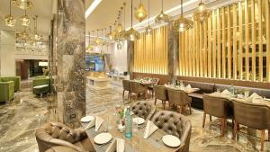 un ristorante con tavoli, sedie e lampadari a braccio di Golden Tulip Essential Jaipur a Jaipur