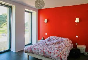 - une chambre avec un mur rouge et un lit dans l'établissement domaine un jour parfait, à Rostrenen