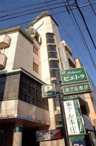 un letrero de la calle frente a un edificio alto en Hotel Honjo, en Honjo