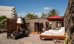 une maison avec un canapé blanc et un parasol dans l'établissement Casa Rural Finca Isabel, à Mozaga