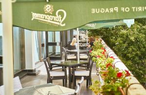 eine Terrasse mit Tischen, Stühlen und einem grünen Sonnenschirm in der Unterkunft Continental Drobeta Turnu Severin in Drobeta-Turnu Severin