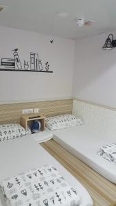 Duas camas num quarto com paredes brancas em K & B Hostel em Hong Kong