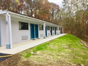 a building with blue doors and a grass field at Hillside Motel Glen Mills in Glen Mills