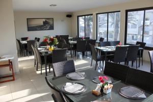 uma sala de jantar com mesas, cadeiras e janelas em Prost Hotel Swakopmund Namibia em Swakopmund