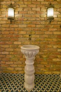 a white sink in front of a brick wall with two lights at Istanbul Life Hotel in Istanbul